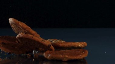 Lezzetli Çikolatalı Kurabiyeler Düşüyor ve Yavaş Hareket Ediyor Karanlık Yansıtıcı Yüzeyde Katı Siyah Arkaplana Karşı Kırıntılarla