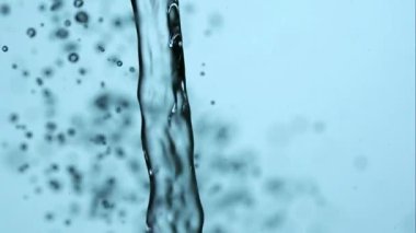 Güçlü, berrak bir su akışının makro yüksek hız görüntüsü. Yavaş çekimde damlacıkların güzel bir modeline sıçrayıp dağılıyor.