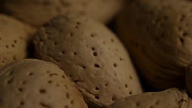 Ekstrem makro, çiğ organik badem fıstığı kabuklarının detaylarını kapatın. Sert doğal dokuları ve şablonları sıcak aydınlatma ve derin gölgelerle gösterin.