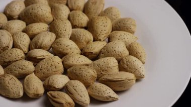 Kabuklarındaki çiğ bademlerle dolu dönen tabaklar sağlıklı vejetaryen besinlerin ve organik tarım ürünlerinin aşçılık kullanımı için üretildiğini vurguluyor.