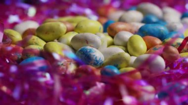 Benekli çikolata paskalya yumurtaları ve renkli oval şekerler mevsimlik bahar arkaplanı için parlak pembe süslemelere yerleştirilmiş.