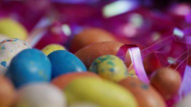 Paskalya kutlamaları ve şenlikli parti dekorasyonları için parlak pembe süslemelerle karışık renkli çikolata yumurtalarını yakın plan yapın.