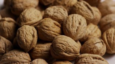 Ekstrem Yakın Çekim: Sağlıklı Beslenme ve Beslenme Konsepti İçin Dokulu Yüzey Detaylarını Gösteren Kabuklu Ceviz Yığının Üzerinde Dönen Kamera