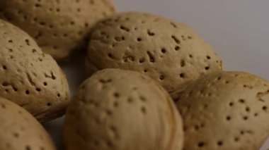 Beyaz arka planda dönen kabuklu çiğ organik bademlerin makro çekimini kapat. Sağlıklı vejetaryen yiyecek malzemeleri.