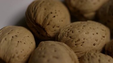 Ekstrem yakın görünüm ham badem kabukları bozulmamış beyaz arkaplan üzerinde yavaş yavaş dönen ayrıntılı dokuyu gösteren makro görünüm