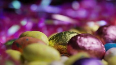 Alüminyum folyoya sarılı çikolata, paskalya yumurtası ve benekli şeker karışımı pembe süs yuvası dönüşümlü tatil ziyafeti.