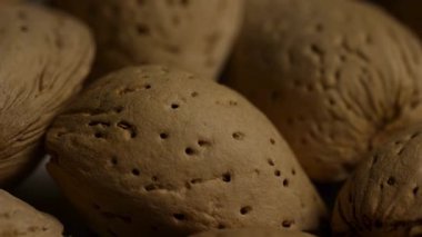 Makro, koyu arkaplanda doğal dokuyu ve gözenekli yüzeyi gösteren kabuklu badem fıstıklarını kapat.