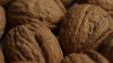 Kabuklu ceviz kabuklarının makro görüntüsünü kapat. Dokulu yüzey yavaşça dönüyor. Doğal detay ve sertliği gösteriyor.