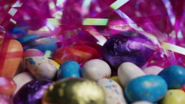 Pembe Tinsel Dönen Bayram Şekerleme Arkaplanı içinde çeşitli Folyo Paketli ve Benekli Çikolatalı Paskalya Yumurtaları