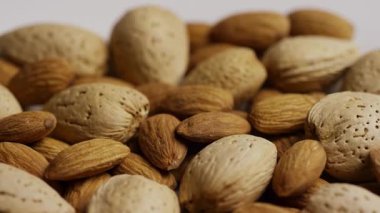 Beyaz zemin üzerinde kabuklu badem ve badem kabukları ile doğal sağlıklı çerez ve organik protein kaynaklarını gösteren dönüşümlü karışım.