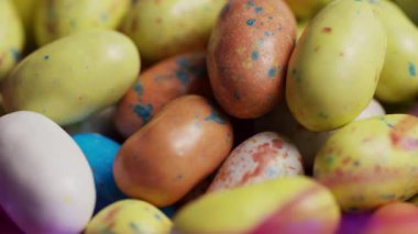 Paskalya bayramı için çeşitli benekli pastel renkli şeker yumurtaları. Pembe plastik çimenlerin içinde yuvalanmış tatlı bir ikram sergiliyorlar.