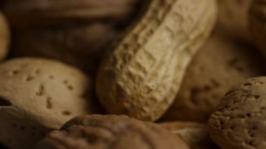 Ekstrem makro, sağlıklı yiyecekler için çeşitli organik dokuları ve şekilleri gösteren kabuklarda yer fıstığı ve ceviz karışımının görüntüsünü kapatır.