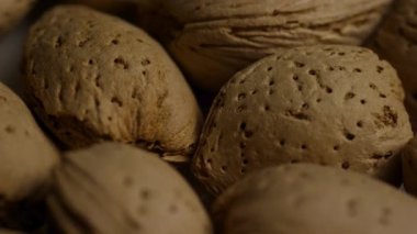 Doğal organik gıda detaylarını ve sağlıklı vejetaryen atıştırmalık malzemelerini vurgulayan sıcak ışıklandırmayla bir araya getirilmiş desenli kahverengi badem kabukları aşırı yakın çekim görüntüsü.