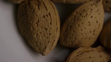 Ekstrem makro yakın çekim görüntüsü desenli badem fıstığı kabukları üzerinde dönüyor gözenekli yüzey detaylarını, doğal organik besin kalıplarını ve sağlıklı atıştırmalıkları vurguluyor.