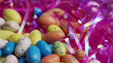 Çeşitli renkli benekli paskalya yumurtaları ve parlak pembe çim karışımı. Bahar bayramı kutlamaları için ekran başında dönüyor. Video klibi.