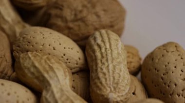 Sert kabuklu ceviz ve badem karışımı bir yığın temiz beyaz yüzey makrosu üzerinde yavaşça dönüyor.