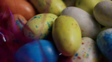 Renkli benekli Paskalya yumurtası şekerlemeleri. Bayram kutlaması ve bahar dekorasyonu için parlak pembe süslemelerle harmanlanmış.