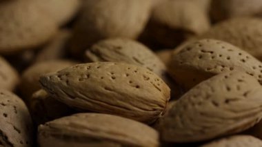 Makro paneller, sağlıklı abur cubur konsepti videosu için doğal dokuları ve kahverengi renkleri gösteren kabuklu badem yığınlarının üzerini kaplıyor.
