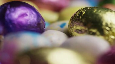 Renkli folyoya sarılı çikolatalı ve benekli çikolata kabuklarına sarılı Paskalya Yumurtalarının Mutlu Tatil Kutlamaları Özgeçmişi