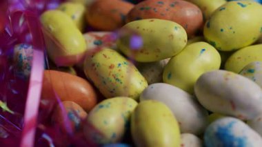 Benekli pastel renkli paskalya yumurtası şekerleri ve mevsimlik tatil teması için parlak pembe dekoratif süslemelerin detaylı görüntüsünü kapat.