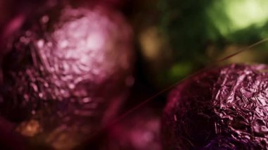 Parlak pembe ve yeşil folyoyla kaplanmış Macro. Bahar bayramı kutlaması ve şeker ikram etmek için çikolatalı yumurta.