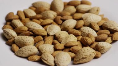 Bir yığın taze badem fıstığı beyaz tabakta düzgünce dönüyor sağlıklı atıştırmalıklar organik gıdalar vejetaryen diyet planı için kaynak