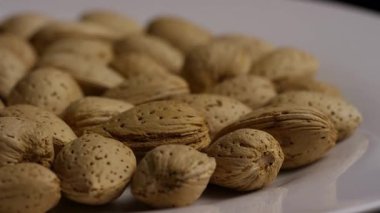 Beyaz tabakta dönen badem fıstıklarının düşük açılı görüntüsü sağlıklı atıştırmalık organik besin kaynağı diyet için