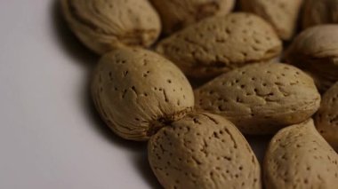 Kahverengi kabuklu çiğ organik badem yığınının makro görüntüsünü kapat ve yavaş yavaş ayrıntılı kaba doku ve doğal beslenme kaynağı aperatiflerini göster