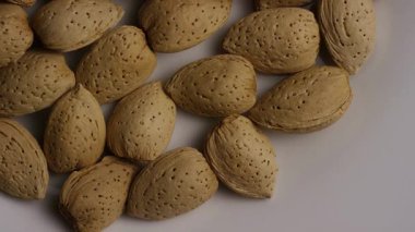 Kabuklu çiğ bademler gevşek bir şekilde beyaz yüzeye yayılmış sağlıklı beslenme ve vejetaryen diyet kavramları ve doğal besin geçmişi için tepeden tırnağa dönüyor.