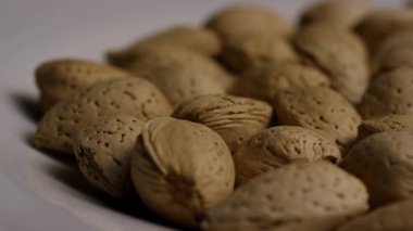 Gözenekli açık kahverengi kabuklu soyulmamış bademler beyaz bir tabakta yığılmıştı. Yavaşça stüdyoyu kapatıyordu. Atıştırmalık sağlıklı şeyler çekiyordu.