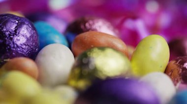 Renkli folyoyla çikolatanın makro fotoğrafını çek. Sığ bir alan derinliği ve pembe bokeh parlak arka plan bulanıklığı var.