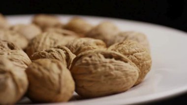 Tüm organik ceviz kabuk yan görünümü beyaz plaka üzerinde düzenlenmiş sert desenli yüzey gösteren siyah arkaplan karşı döner