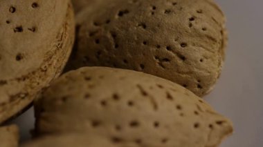 Kahverengi desenli badem cevizlerinin üst üste istiflenmiş ve beyaz arka planda yavaşça dönen aşırı yakın görünümü