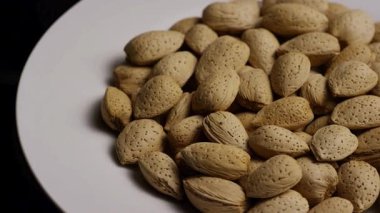 Temiz beyaz bir arka planda sert desenli kabuklu organik badem fıstıklarının dönüşümlü yığını