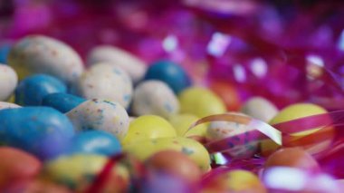 Benekli paskalya şekerli pastel yumurtaların dönüşümlü çekimini kapat. Parlak pembe çimenlere yerleştirilmiş.