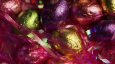 Pembe dekoratif süslemelere gizlenmiş folyoyla sarılan paskalya yumurtalarının yukarıdan aşağı dönüşümlü görüntüsü