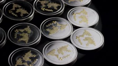 Çoklu parlak kripto para birimleri dramatik ışıklandırma altında koyu yansıtıcı yüzeyde düzenli olarak düzenlenmiştir.