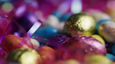 Dekoratif sepete yerleştirilmiş renkli folyolu yumurtalar sığ tarla derinliğinde bayram atmosferi yaratıyor.