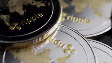 Yığılmış metalik dijital para birimlerine yakın görünüm ve kabartmalı dünya haritası karanlık finansal konsept ayarlarına ışığı yansıtıyor