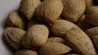 Kabuklu bademler bir araya toplanarak yumuşak stüdyo ışıkları altında doğal sağlıklı gıda arka planı oluşturur.