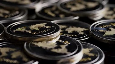 Karanlık ortamda üst üste yığılmış çoklu metalik madeni paralar oyulmuş detayları ve makro perspektif üzerinden yansıtıcı yüzeyleri vurguluyor