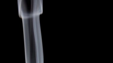 Karanlık bir ortamda zarif bir şekilde yükselen ince beyaz dumanın büyüleyici görüntüsü.