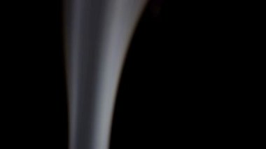 Yavaş çekim beyaz duman güzel kıvrımlar yaratır ve karanlığa doğru yükselir..