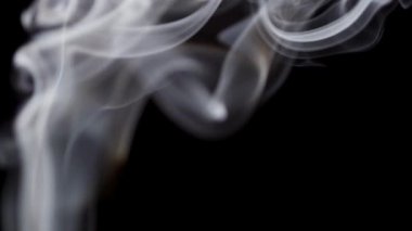 İnce beyaz duman izleri karanlıkta zarifçe ilerler ve geçici desenler bırakır..