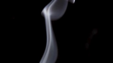 Beyaz dumandan oluşan uzun bir kolon, çerçevenin altından siyaha karşı dikey yükselir..