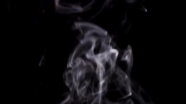 Beyaz duman, siyah bir arkaplanda yükselen güzel kıvrımlar ve spiraller oluşturur..