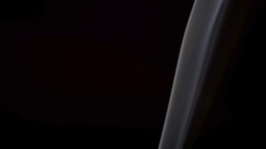 Beyaz duman, dağılmadan önce siyah bir arkaplanda görünür bir sütunda yükselir..