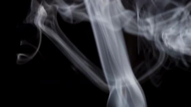 Beyaz duman, siyah bir zemin üzerinde yükselen sarmal ve sarmalları oluşturur..