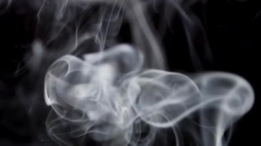 Hassas beyaz duman izleri zarif bir şekilde karanlık bir arkaplanda hareket eder..