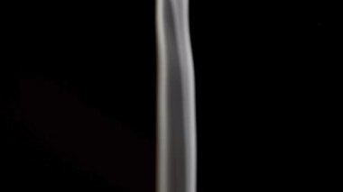 Çok ince ve narin bir beyaz duman çizgisi, nazik dalgalar ve salınımlarla dikey olarak yükselir ve minimalist bir atmosferik görsel etki yaratır..